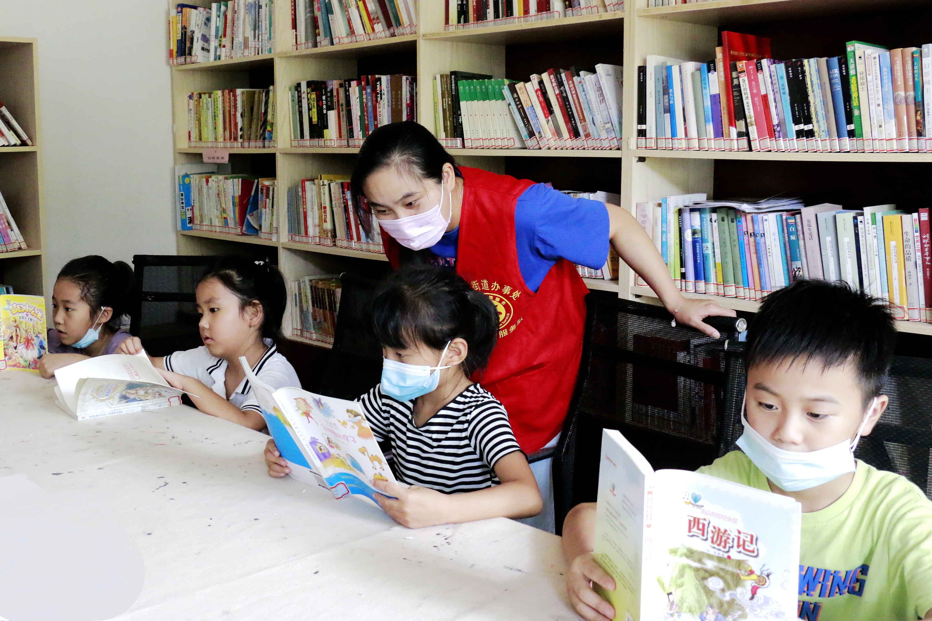 文化站留守儿童之家图书室,新时代文明实践志愿者在指导孩子们读书